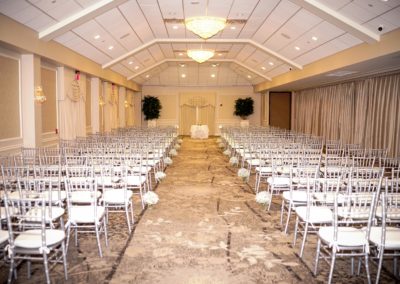 The Atrium room at Springfield country club setup with white chairs four on each side of wedding aisle.