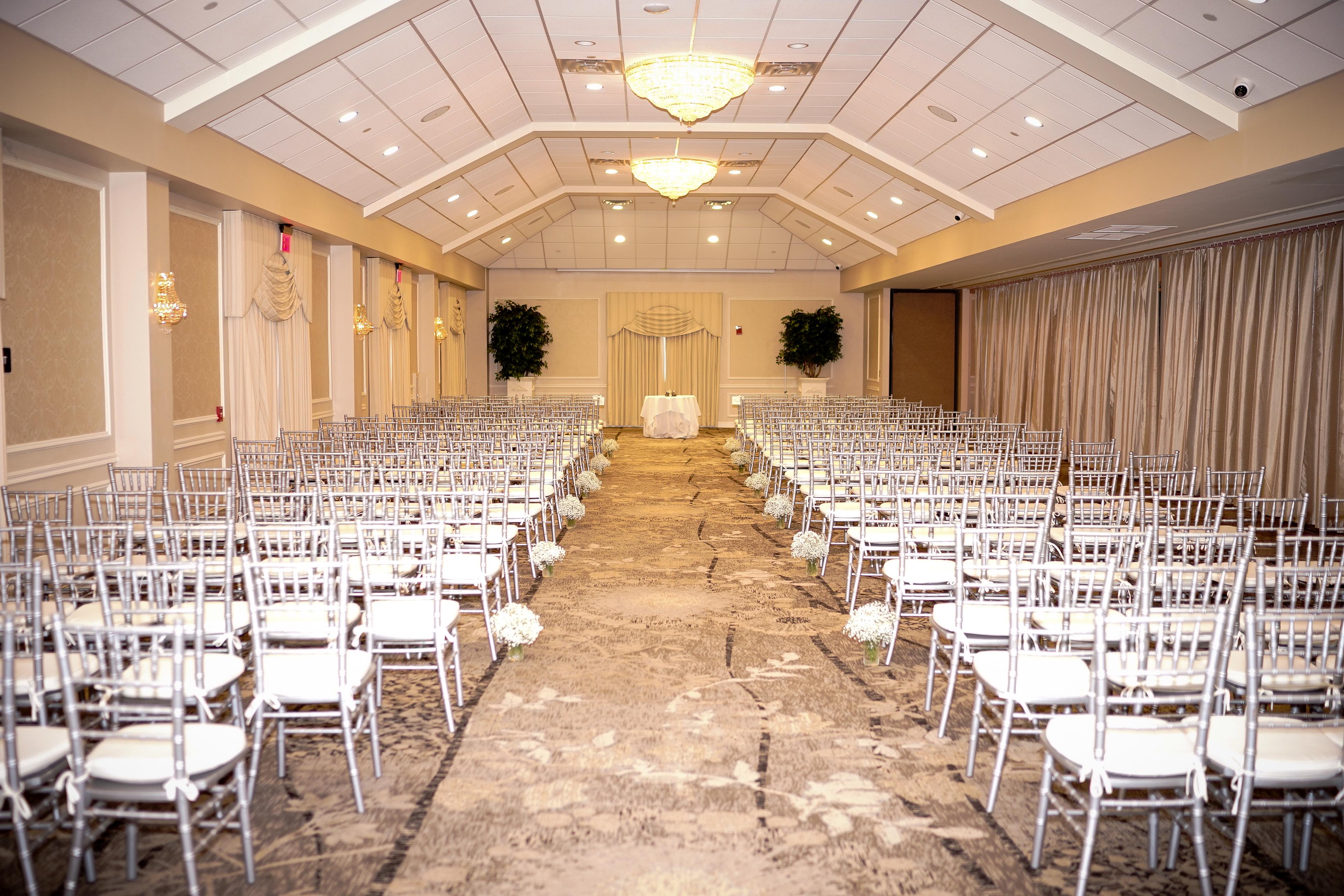The Atrium room at Springfield country club setup with white chairs four on each side of wedding aisle. 