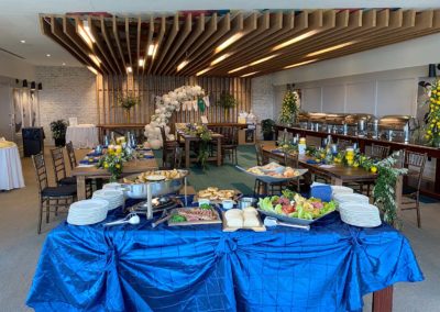 Table with assorted appetizers covered with blue linen with banquet room in background.