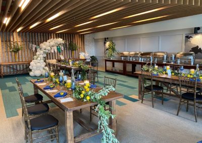 Four wooden tables with blue, green and yellow decor in a banquet room.