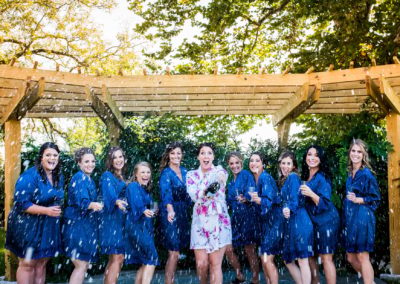 Bridesmaids popping a bottle of champagne outdoors