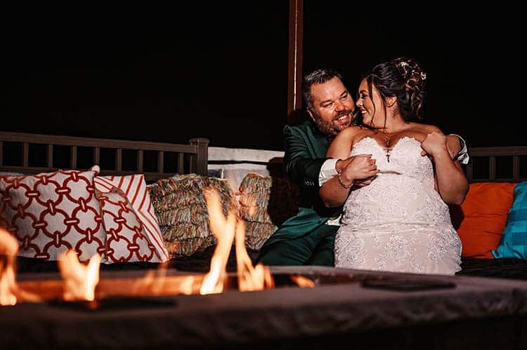 Bride and Groom cuddling in front of a fire at night. Image by Olga Hinchman Photography.