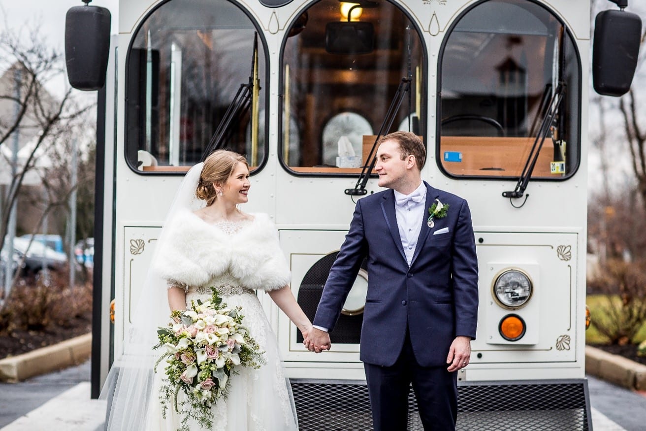 Bride And Groom Holding Hands In Front Of Wedding Trolly