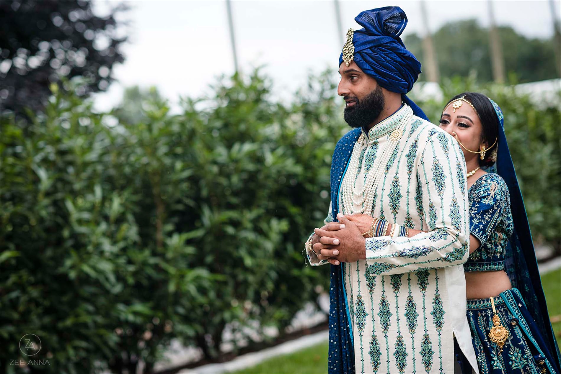 Multicultural bride hugging groom from behind him. Part of first look wedding ideas blog.