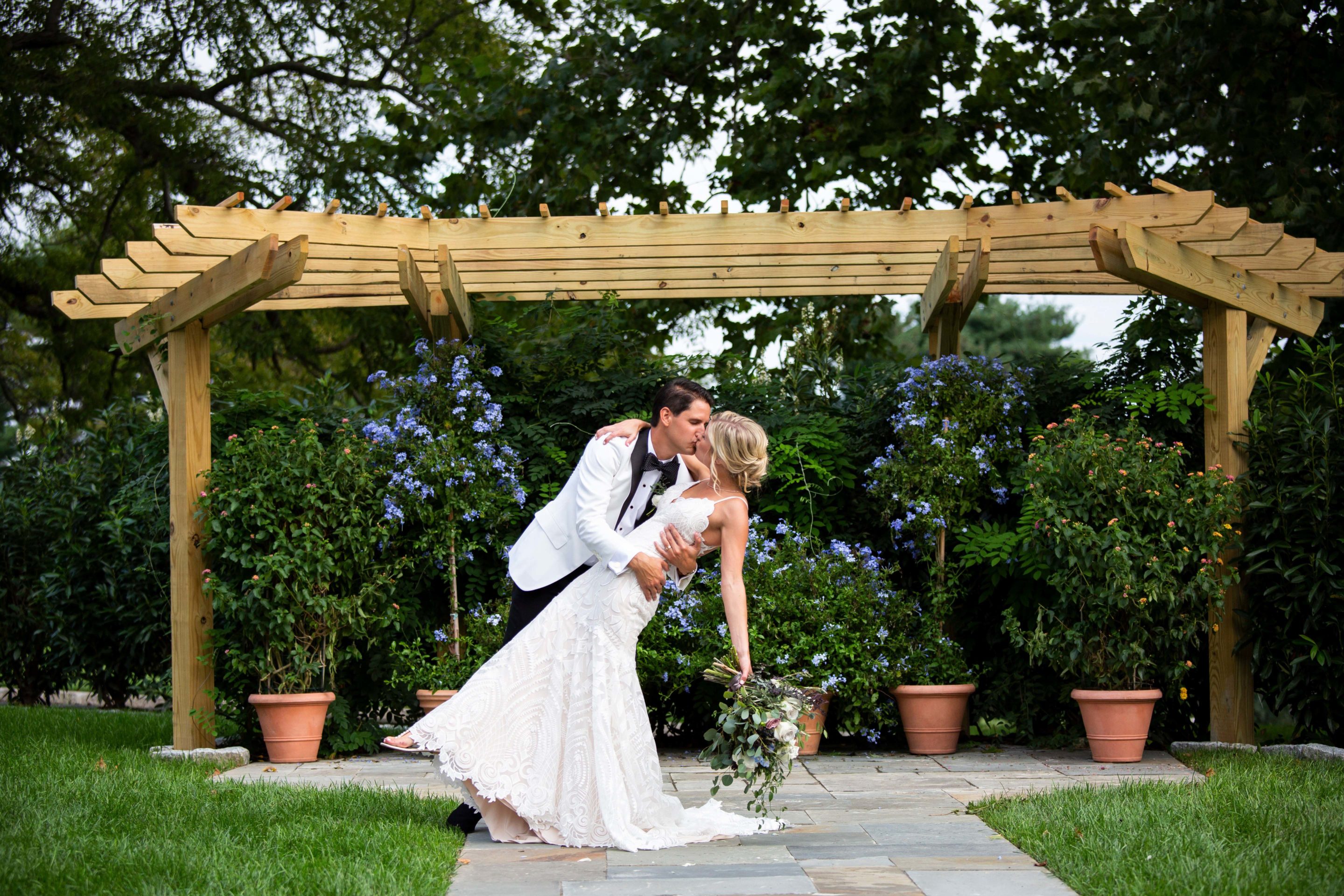 Bride and Groom Kissing at Outdoor Ceremony Surrounded by Folliage