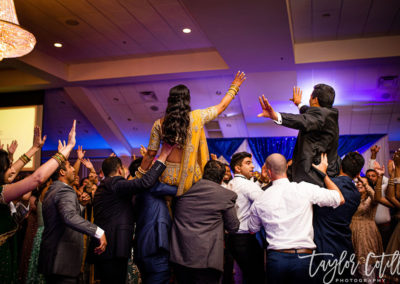 Multicultural wedding bride and groom hoisted on shoulders after being married.