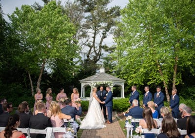 Outdoor wedding ceremony at the Gazebo. Bride and groom at altar with officiant and bridal party on either side of them.