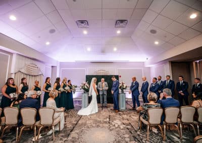 Indoor wedding ceremony of bride and groom at the altar with the officiant and bridal party beside them in the Atrium