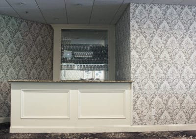 Fairway Ballroom with floral patterned carpets and walls with built in bar with glassware and a mirror behind it.
