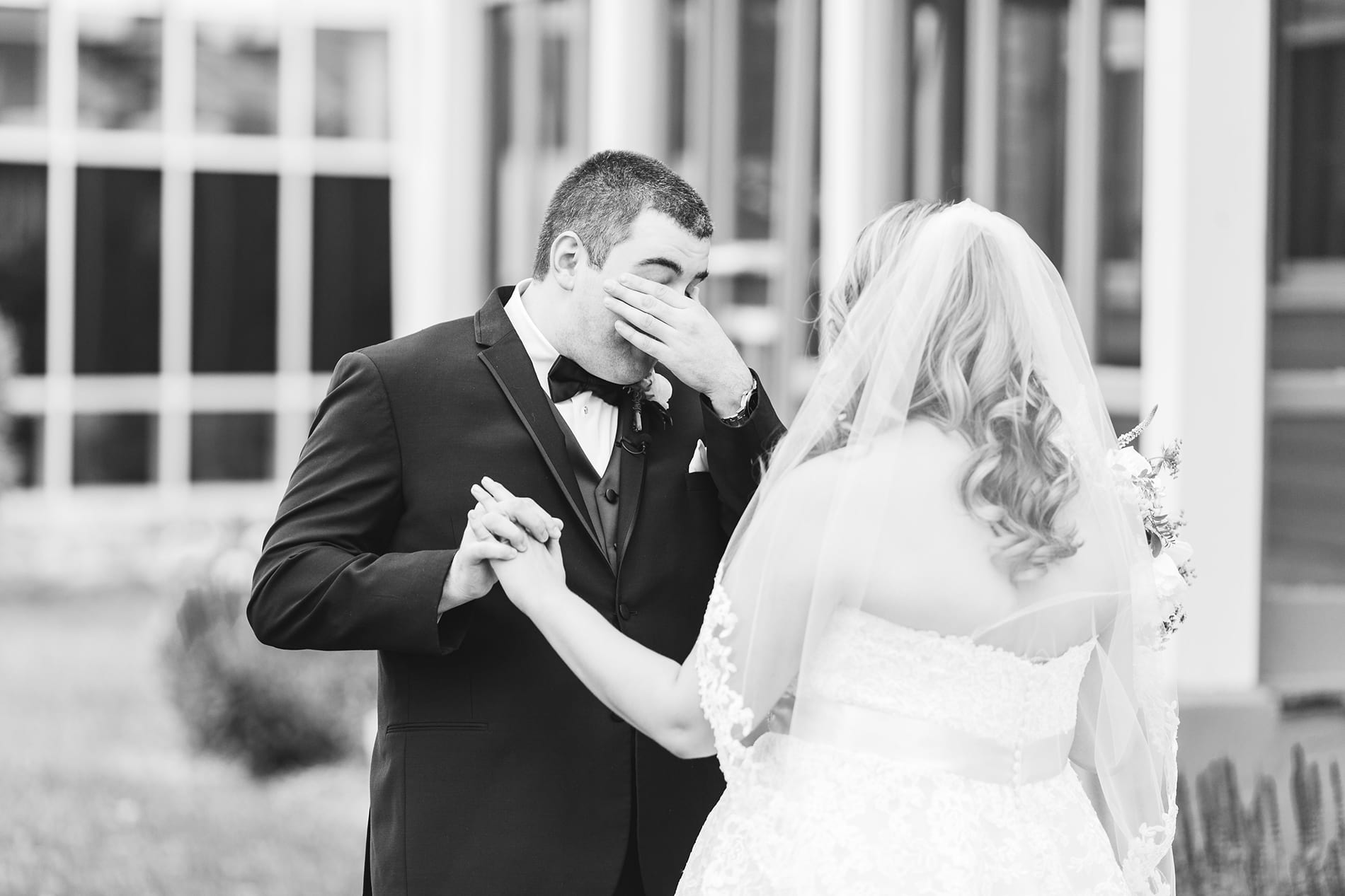 Groom overwhelmed wipes tears from his eyes while holding the bride's hand. Part of first look wedding ideas blog.
