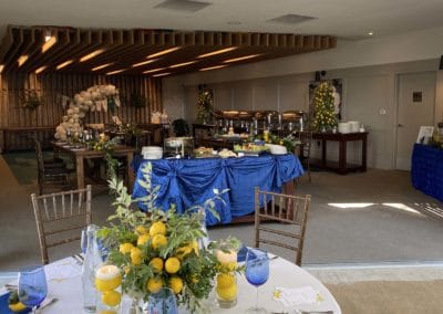 Banquet room in background with white round table in foreground with lemon centerpiece