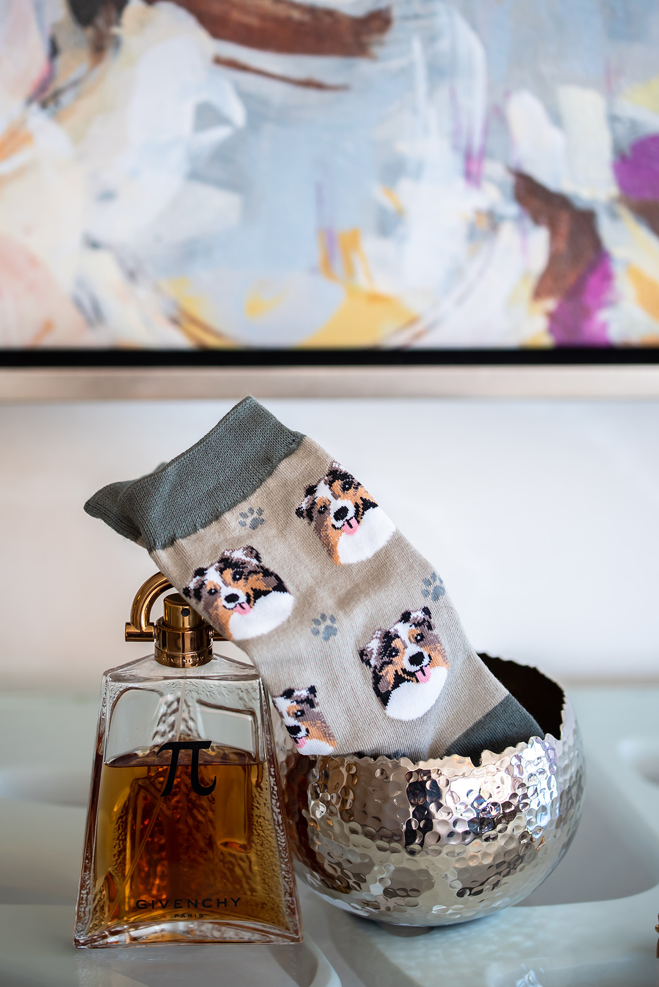 Socks with collie and paw prints on it sitting next to a bottle of cologne.   Photo by Maria J Photography