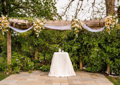 Outdoor wedding ceremony altar setup with sunflower floral displays on trellis at the Ceremony Garden