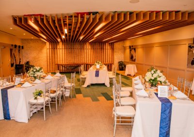 Rectangular banquet tables covered in white linen with blue table runners in banquet room.