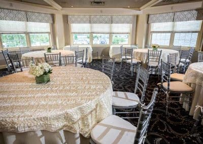 Reserve Room at Springfield Country Club decorated in white and tan colors with round tables with white flower center pieces.