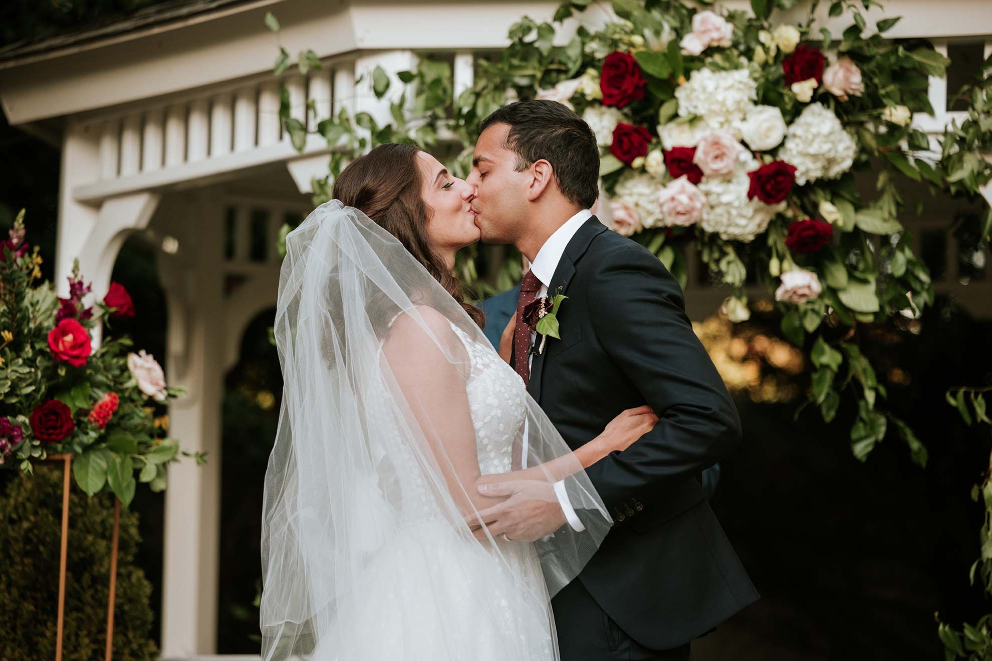 Close up bride and groom kissing with the 2023 trending flowers in the background.