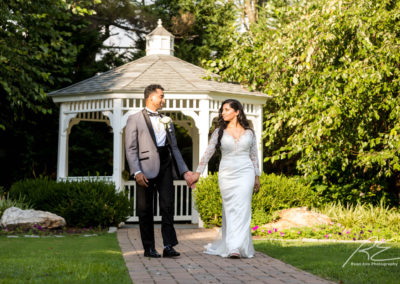 Bride and Groom holding hands in front of a gazebo.
