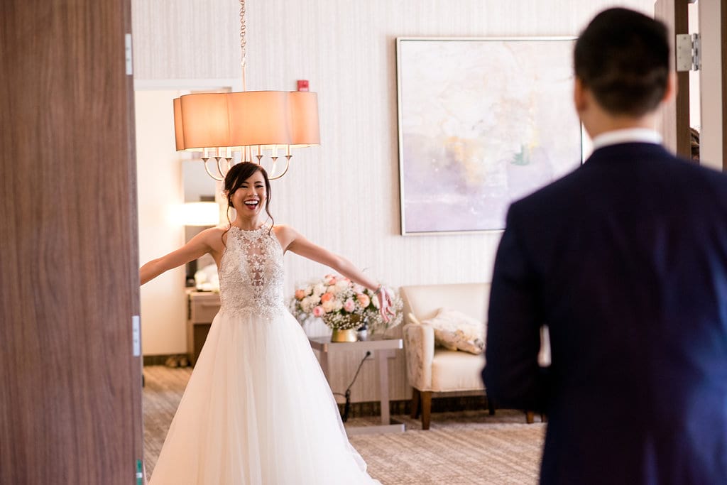 Groom walking into the bride's room with the bride's hand out wide, surprise!